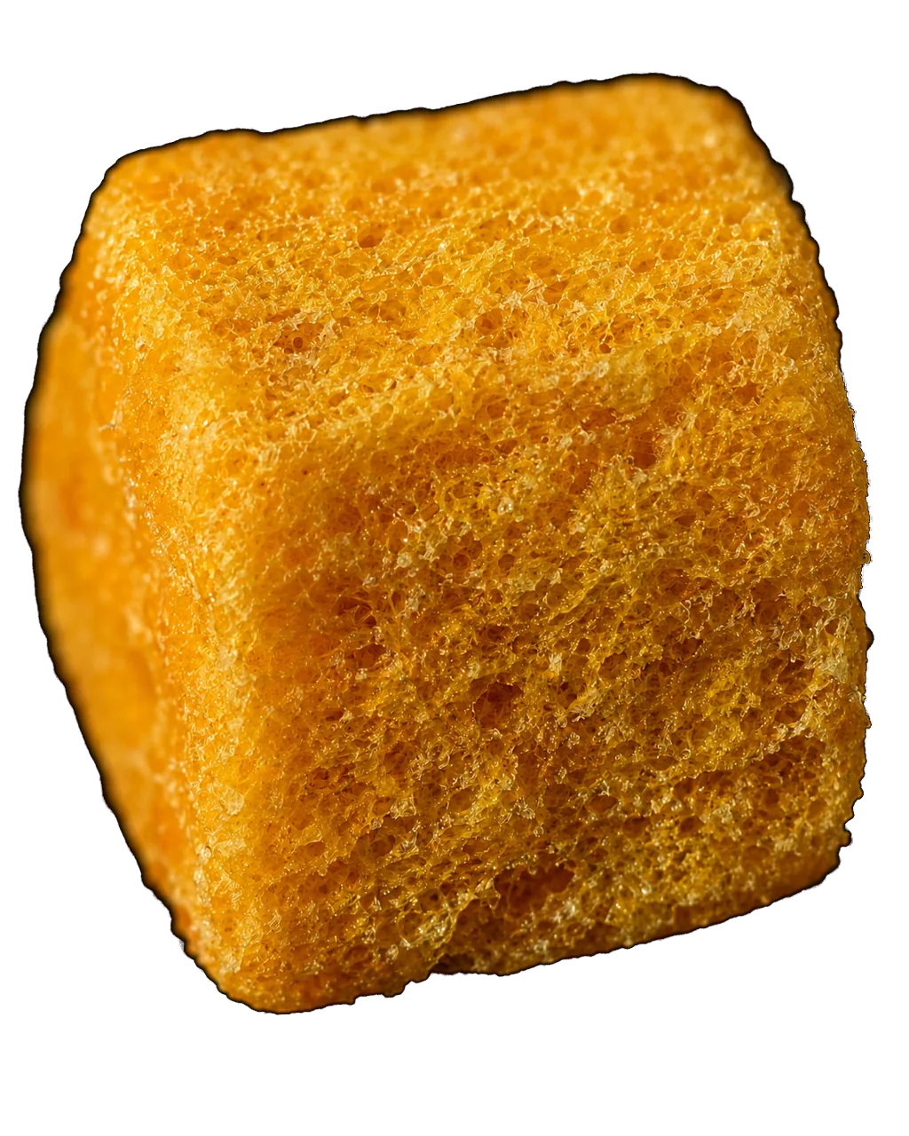 Close macro of a single freeze-dried Alphonso mango chunk, showing its dry porous structure